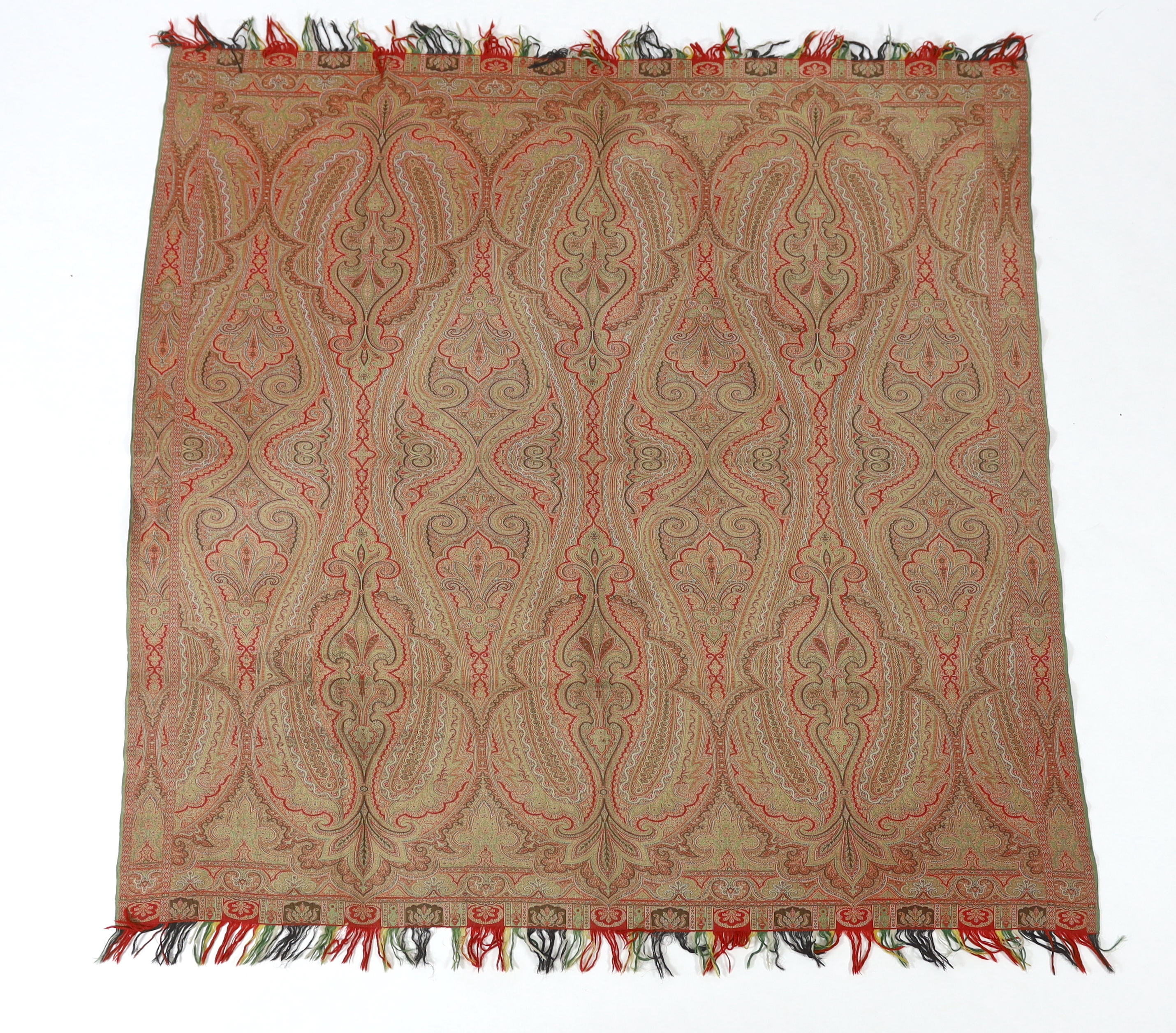 An 1860’s, reversible woven wool Paisley shawl, woven with green, red, ochre and brown, with a woven border and fringing both ends. 166cm wide x 169cm long